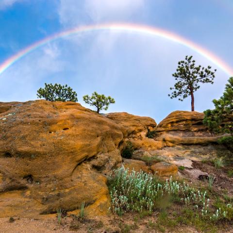 photo of a double rainbow above rocky bluffs